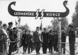 Quisling ved Germanske SS Norges leirportal under «Borrestevnet» i Borre nasjonalpark pinsen 1943. Bak Qusling, i svil, er Thore Tjersland (1893–1964), NS' fylkesfører i «Vestre Viken» fra 1. november 1942 .[9] Foto: Riksarkivet